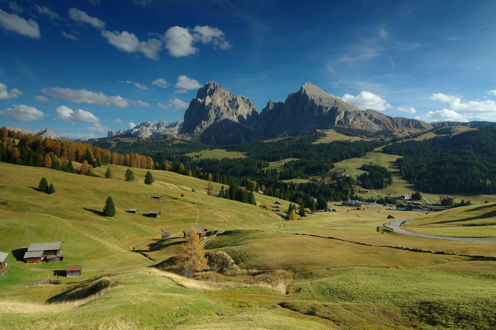 L'Alpe di Siusi con le baite sui prati e il Sassolungo sotto il cielo d'estate